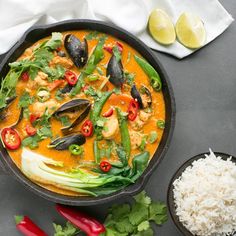 a skillet filled with seafood and rice next to some garnishes on a table