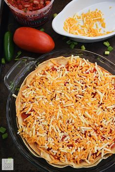 a pizza sitting on top of a pan covered in cheese next to tomatoes and peppers