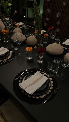 the table is set with black plates and silverware