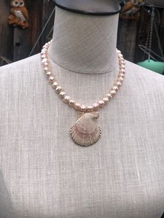 a necklace on a mannequin with a shell charm