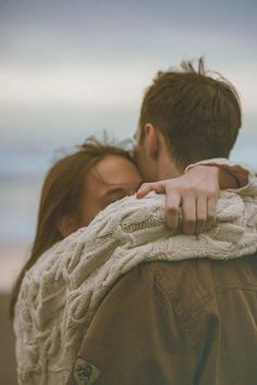 a man and woman embracing each other on the beach