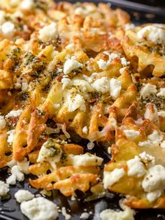 a close up of food on a pan with broccoli and feta cheese