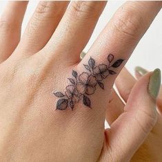 a woman's hand with a flower tattoo on the left side of her ring