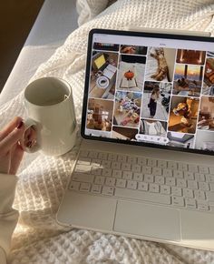 a laptop computer sitting on top of a bed next to a white cup and saucer