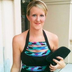 a woman in a black and blue dress holding a hat on her left hand while standing next to a building