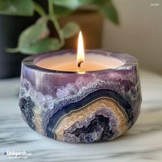 a candle that is sitting on top of a table next to a potted plant