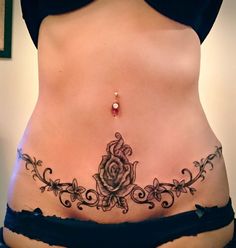 a woman's stomach with a rose tattoo on the side and black lace around it