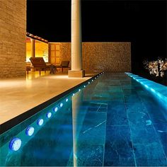 an outdoor swimming pool at night with blue lights