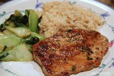 a white plate topped with meat and veggies next to brown rice on top of a table