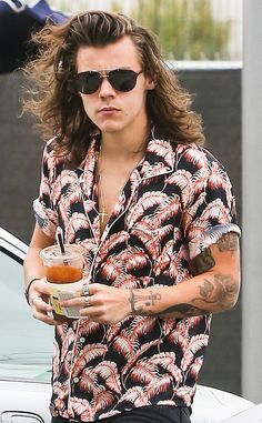 a man with long hair and sunglasses holding a drink