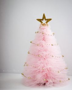 a pink and gold christmas tree with a star on top, sitting in front of a white background