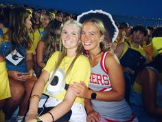 two young women sitting next to each other at a tennis match, both wearing yellow shirts and white shorts