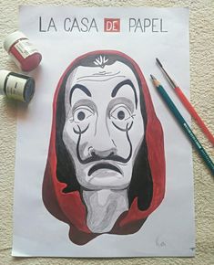 a paper with a drawing of a man's face on it next to some markers