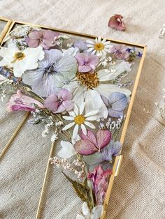 an open box with flowers on it sitting on a table next to some dried flowers