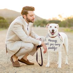 a man kneeling down next to a dog holding a sign that says mommy can you marry?