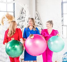 three women are holding balloons and smiling at each other