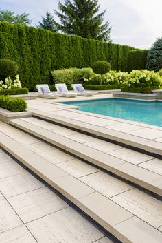 an outdoor swimming pool with steps leading up to it and landscaping surrounding the pool area