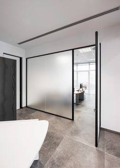 an empty office with frosted glass walls and black door handles on the doors,