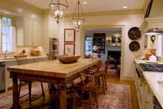 a large wooden table sitting in the middle of a kitchen next to a stove top oven