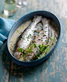 an image of fish in a pan with herbs on the side for garnish