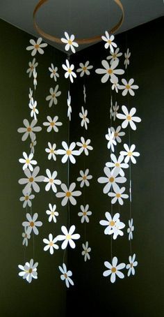 some paper flowers hanging from the ceiling in front of a green wall with a circular light fixture