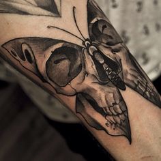 a man's arm with a skull and butterfly tattoo on it