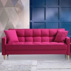 a fuchsia colored couch in front of blue and pink wall with geometric design