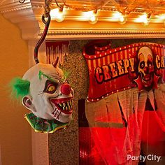 two creepy clown masks hanging from the ceiling in front of a mirror with lights on it