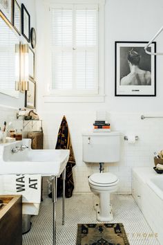 a white bathroom with a sink, toilet and bathtub next to a framed black and white photo