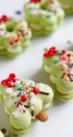 green macaroons decorated with candy and sprinkles on a white surface