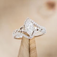 a diamond ring on top of a wooden stand