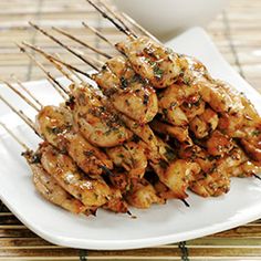 several skewers of food sitting on a white plate next to a cup and saucer