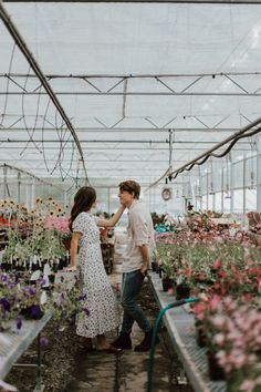 two people in a greenhouse looking at flowers