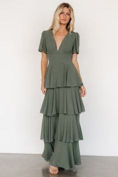 a woman wearing a green dress with tiered ruffles and a v neckline