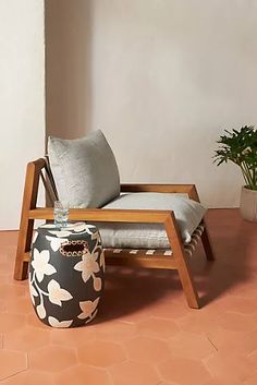 a chair and ottoman sitting on a tile floor next to a potted plant in a corner