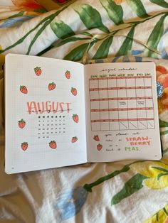 an open planner with strawberries on it and the word august written in cursive writing