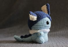 a crocheted blue and white stuffed animal sitting on top of a gray surface