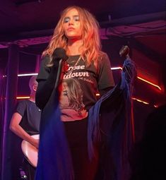 a woman with long hair standing on stage