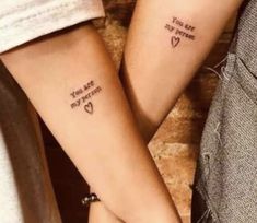 two people holding hands with tattoos on their arms