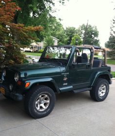 a green jeep is parked in front of some trees