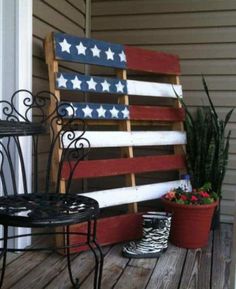 an american flag made out of wood sitting on top of a porch next to a potted plant