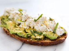 an avocado toast with ricotta, olive oil, lemon zest and basil