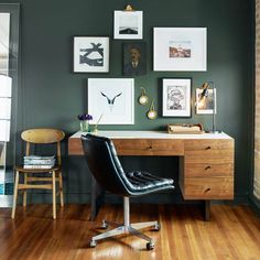 a desk with a chair and pictures on the wall above it in an office space