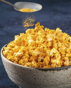 a spoon scooping some yellow popcorn out of a bowl