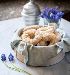 a basket filled with donuts sitting on top of a table next to blue flowers