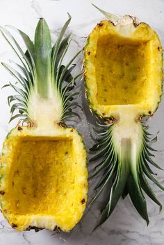 two pineapples cut in half on a marble counter top with one being eaten