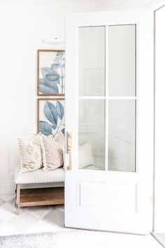 a room with a white door and some pillows on the bench in front of it