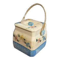 a blue and white basket with flowers painted on the side, holding a wicker handle