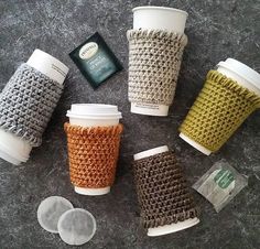 six coffee cups are lined up on the floor next to each other and one cup has been made out of knitted material