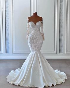 a white wedding dress with long sleeves and an off the shoulder neckline, on a mannequin